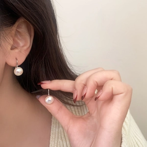 Close-up of 9mm round white pearl drop earrings worn on model for an elegant french look
