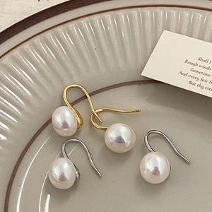 Elegant French style pearl drop earrings in gold and silver finishes on a ceramic plate