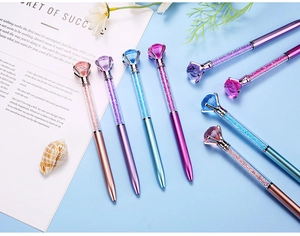 Detailoverzicht van kristallen diamant balpennen in diverse kleuren op een blauwe ondergrond