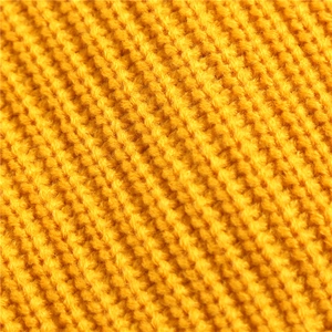 Macro detail of yellow knitted fabric showing soft wool texture and intricate weave patterns
