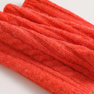 Dettaglio di una sciarpa rossa in maglia con trama a treccia spessa
