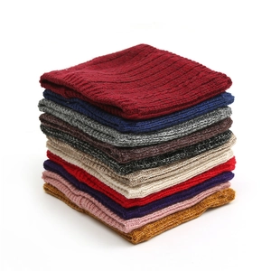 Close-up of thick cable knit neck warmers stacked in ten solid winter colors
