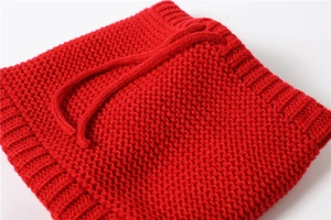 Detail of red cable knit neck warmer featuring ribbed edges and adjustable drawstring