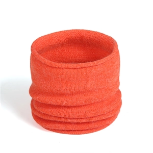 Macro detail of bright orange knit neck warmer showing elastic ribbed texture and stitching
