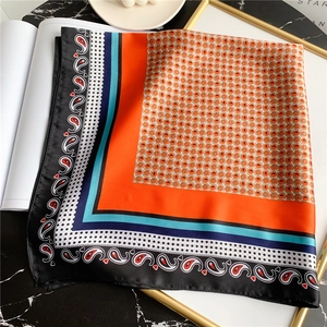 Détail d'un foulard carré en soie avec motif paisley orange et bleu et pois élégants