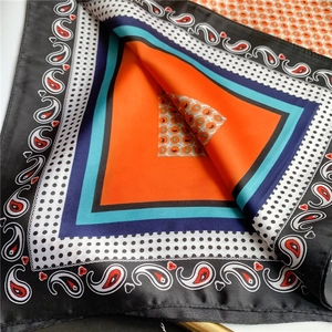 Détail d'un foulard en soie à motif paisley avec centre orange et bordures à pois