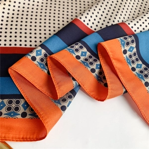 Détail montrant la texture soyeuse du tissu et les motifs géométriques du foulard