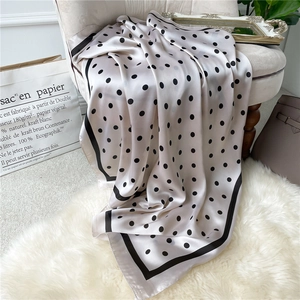 Close-up of silk-like polka dot scarf showing its smooth texture on a velvet chair