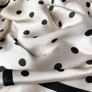 Macro view of polka dot silk scarf texture with elegant black border and satin finish