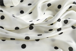 Macro shot of ivory silk square scarf with classic black polka dots and smooth texture
