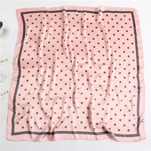 Detail of pink polka dot silk square scarf with soft satin texture and elegant folds