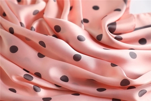 Macro shot of light pink silk scarf fabric with dark polka dots and satin finish