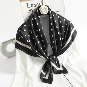 Elegant black silk square scarf with white polka dots tied on a white shirt collar