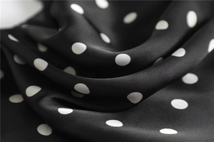 Close-up of elegant black and white polka dot satin fabric with smooth silk texture
