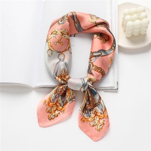 Gros plan d'un foulard en soie rose à motif chaîne dorée drapé sur un livre de mode