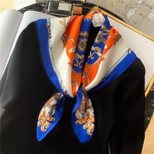 Détail d'un foulard en soie aux motifs de chaînes royales noué sur un pull noir pour l'élégance