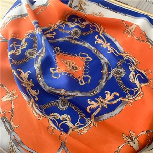 Détail d'un foulard en soie avec motifs de chaînes équestres bleu roi et orange