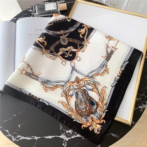 Détail d'un foulard carré vintage avec imprimé chaîne baroque dorée sur marbre