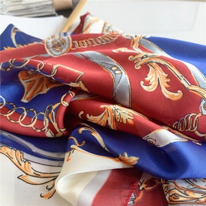 Détail du motif chaîne baroque sur foulard en soie rouge et bleu au fini brillant