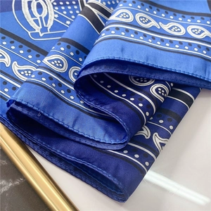 Gros plan d'un foulard en satin bleu à motifs cachemire, pois blancs et coutures fines
