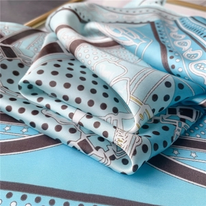 Gros plan détaillé montrant la texture satinée et le motif à pois sur une écharpe bleu clair