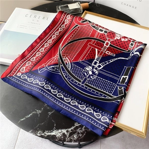 Détail d'un foulard en soie rouge et bleu avec motifs paisley sur fond marbre