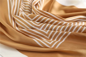 Gros plan d'un foulard en soie rayé marron doré et blanc avec un drapé élégant