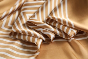 Gros plan d'un foulard en soie jaune moutarde avec des rayures géométriques blanches