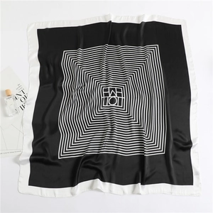 Détail d'un foulard carré soyeux avec des motifs géométriques de rayures noires et blanches