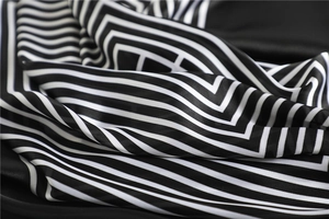 Détail de l'écharpe en soie à rayures avec finition satinée et motif noir et blanc moderne