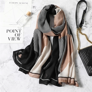 Detail of color-block scarf with geometric stripes and heart print on marble surface
