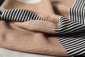 Close-up of geometric striped scarf showing soft knit fabric and fine texture in camel