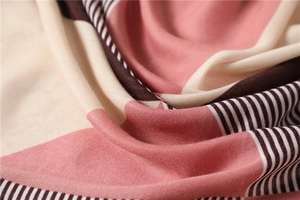 Macro detail of geometric patterned scarf showing pink, beige and brown woven fabric