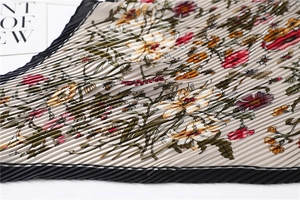 Detail of floral printed pleated silk scarf featuring black contrast edges and lily patterns