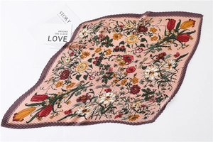 Detail of pleated pink silk scarf featuring intricate floral prints and wavy texture