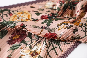 Detailed macro view of pleated silk scarf featuring floral and insect print patterns