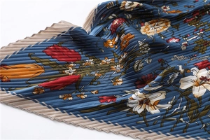 Detailed close-up of pleated silk scarf with vintage floral patterns and sharp textures