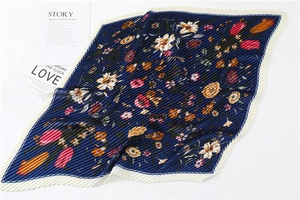 Detail of blue floral print silk scarf featuring fine pleats and vibrant tulip patterns