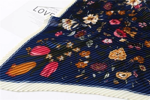 Detail showing pleated floral silk scarf texture with blue background and orange flowers