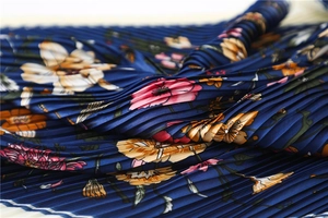 Macro shot of navy blue pleated satin scarf with pink and yellow floral patterns