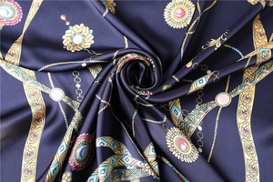 Vue macro d'un foulard en soie bleu marine avec chaînes dorées et motifs gemmes
