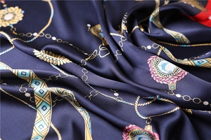 Gros plan sur un foulard en satin bleu marine avec chaînes dorées et bordure rouge