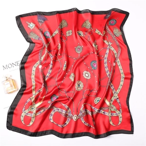 Détail d'un carré de soie rouge avec motifs chaînes dorées et bordures satin noir