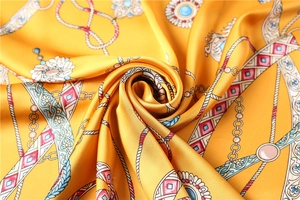Gros plan détaillé d'un foulard en soie dorée avec des motifs de chaînes et bijoux