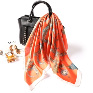Foulard en soie orange avec motif chaîne vintage drapé sur un sac à main noir élégant