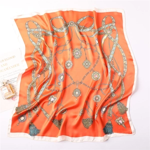 Détail d'un carré de soie orange avec motifs de chaînes de bijoux et de perles