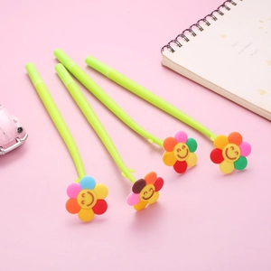 Set of 4 cute flower-topped green gel pens with smiling sun flower charms on pink background