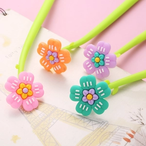 Close-up of a four-piece set of colorful flower pens with green stems on a notebook