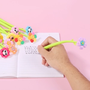 Close-up of colorful floral silicone pens being used for writing on a pink background