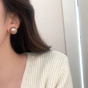 Elegant large matte gold spherical stud earrings shown on a model for a minimalist look